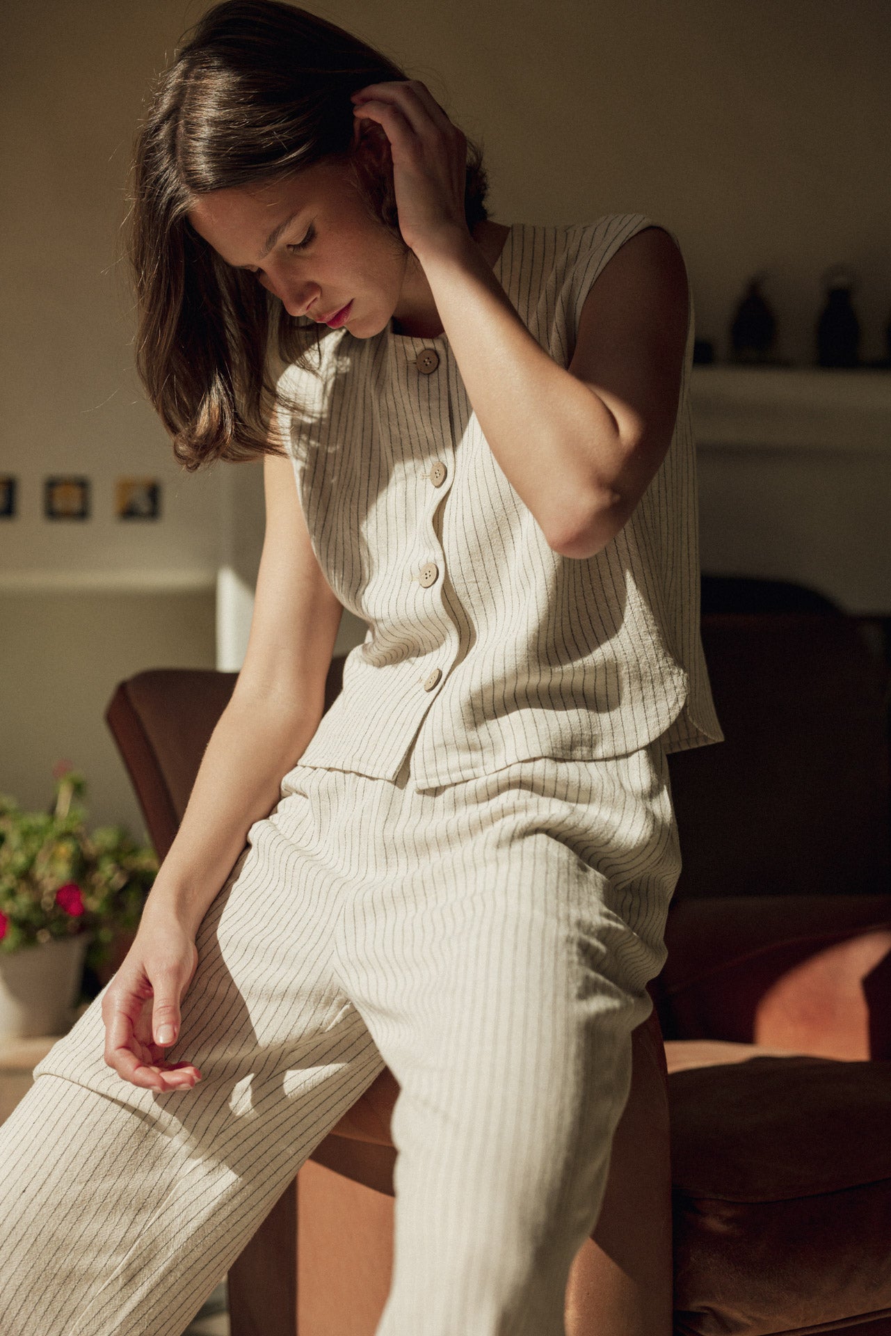Woman in a light-colored outfit sitting on a couch in a cozy living room.
